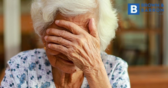 elderly woman covers her face in despair
