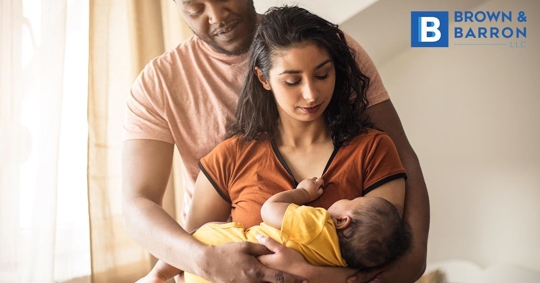 Man & woman cuddle newborn
