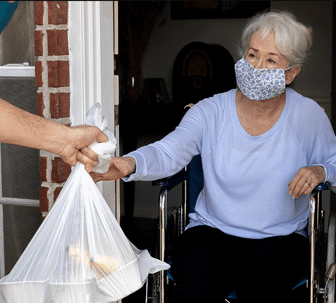 Masked elderly woman receives food at her door