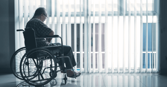 elderly man sitting in wheelchair by the window